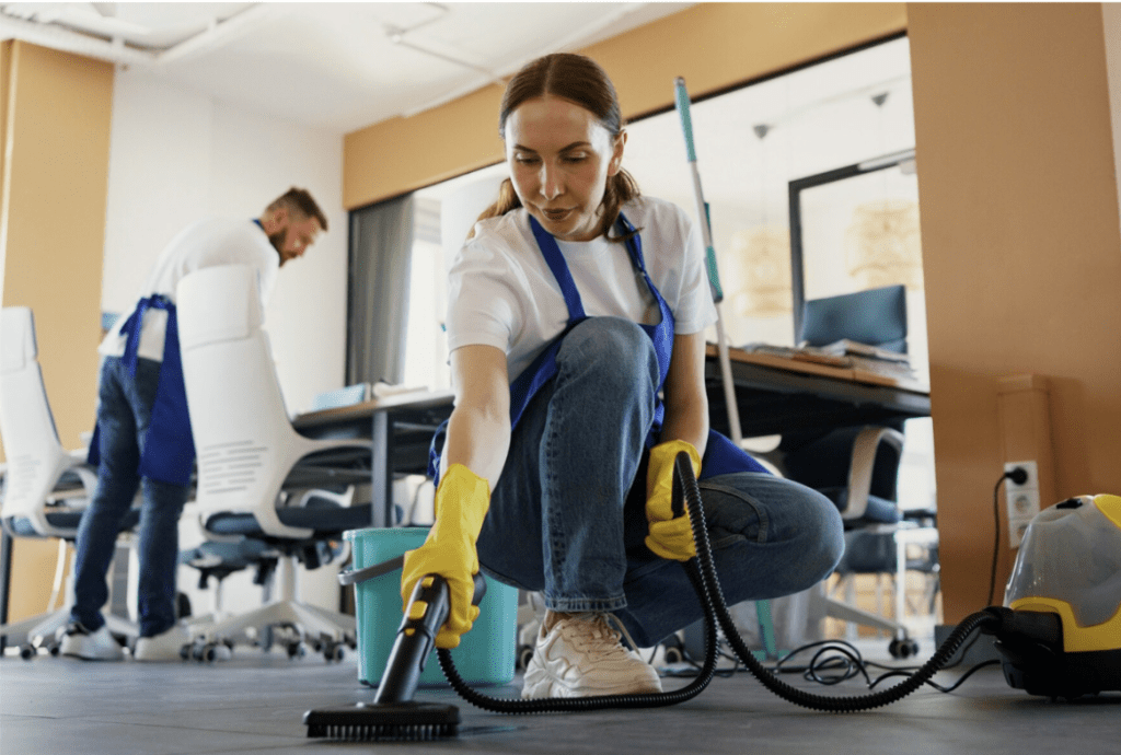 Mujer realizando limpieza de oficinas con aspiradora en un ambiente de trabajo