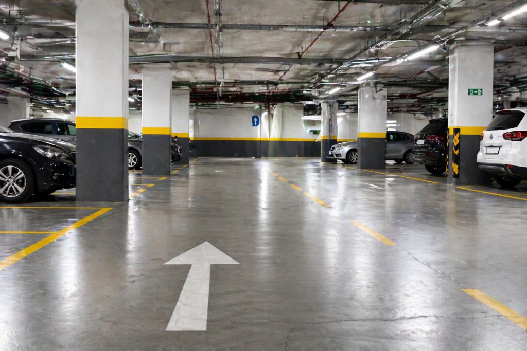 Limpieza de parking Vista limpia y ordenada de un aparcamiento subterráneo con pavimento de concreto, espacios de estacionamiento marcados y columnas de concreto.